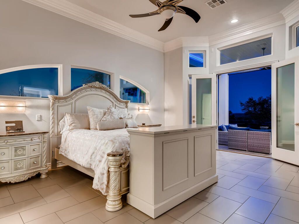 A bedroom with a large bed and a ceiling fan
