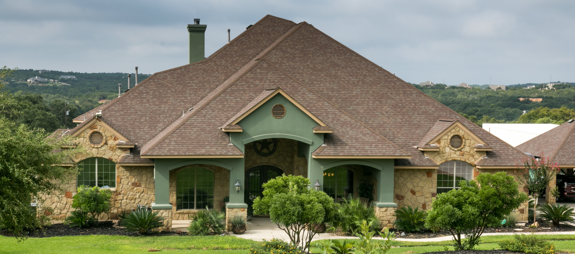 A large house with a brown roof and green trim