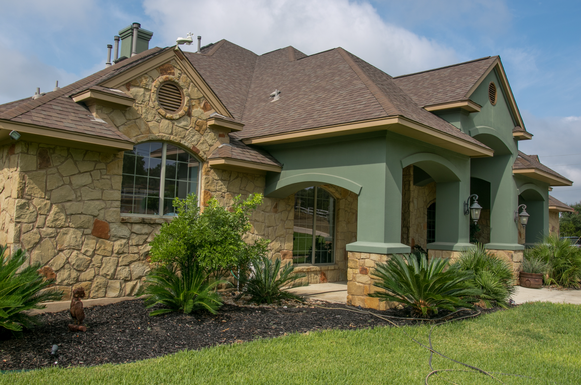 A large house with a brown roof is sitting on top of a lush green lawn.