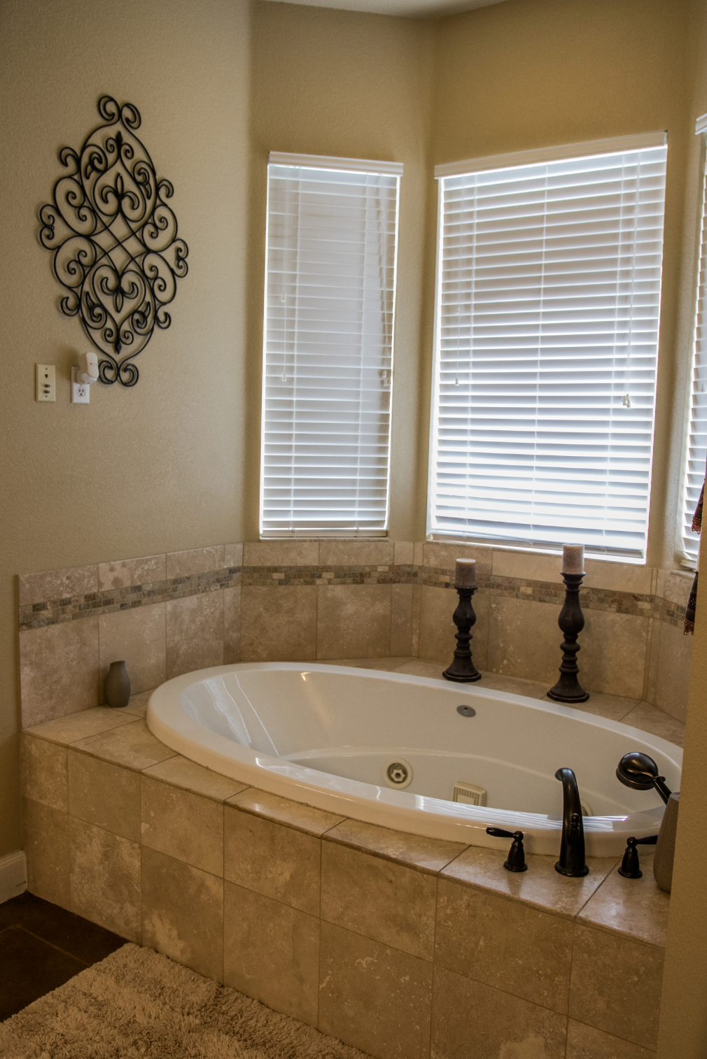 A bathtub in a bathroom next to a window with blinds.