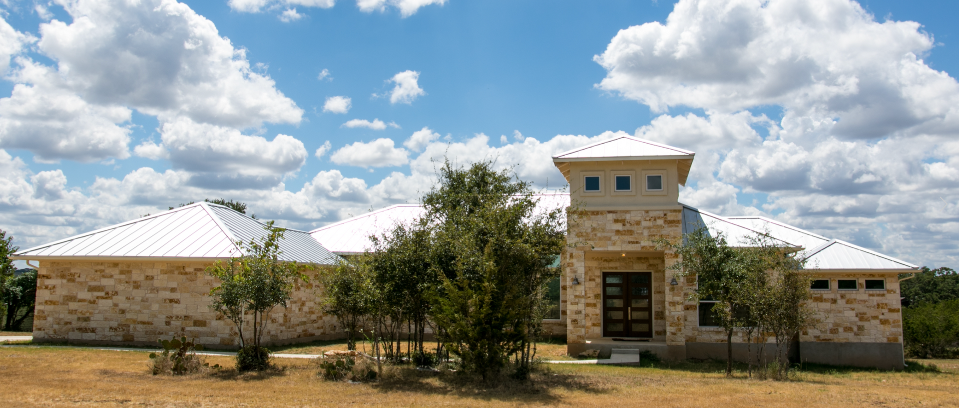 A large house with a white roof is sitting in the middle of a field.