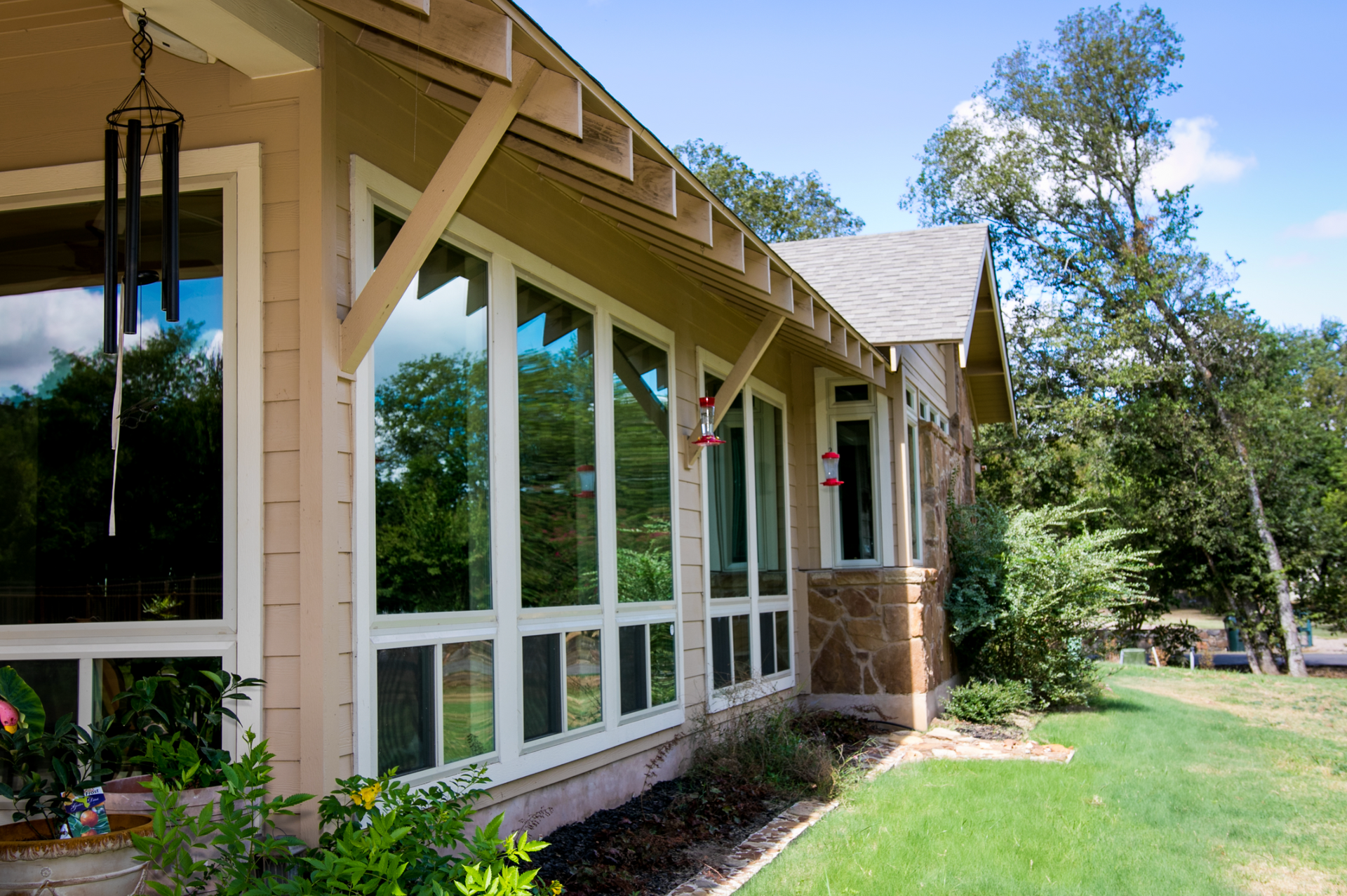 A house with lots of windows and a wind chime on the porch