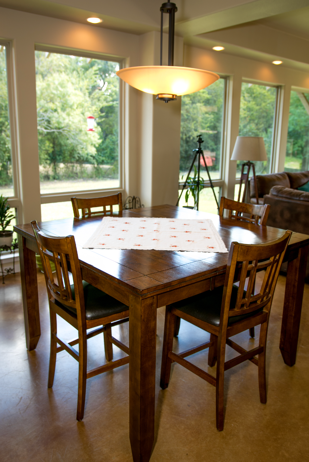 A dining room table with four chairs and a lamp hanging from the ceiling