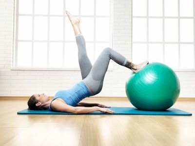 Una donna è sdraiata su un tappetino da yoga con una palla da pilates.