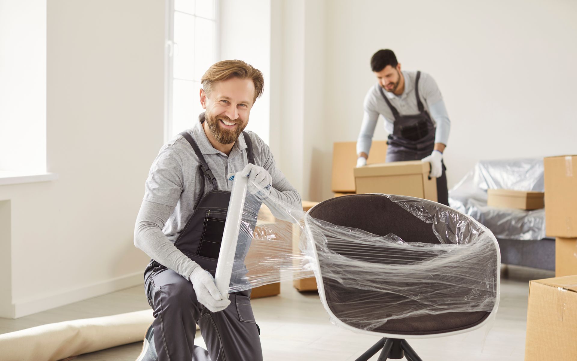 A male worker covering furniture with plastic for storage or moving services. A male worker covering furniture with plastic for storage or moving services.