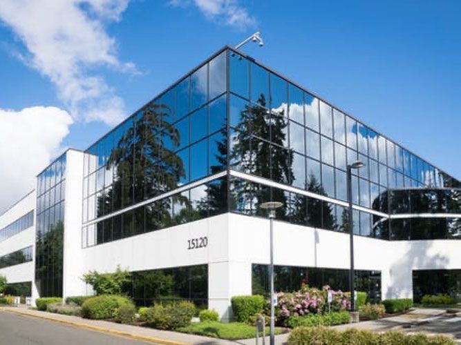 A large office building with a lot of windows and trees in front of it .