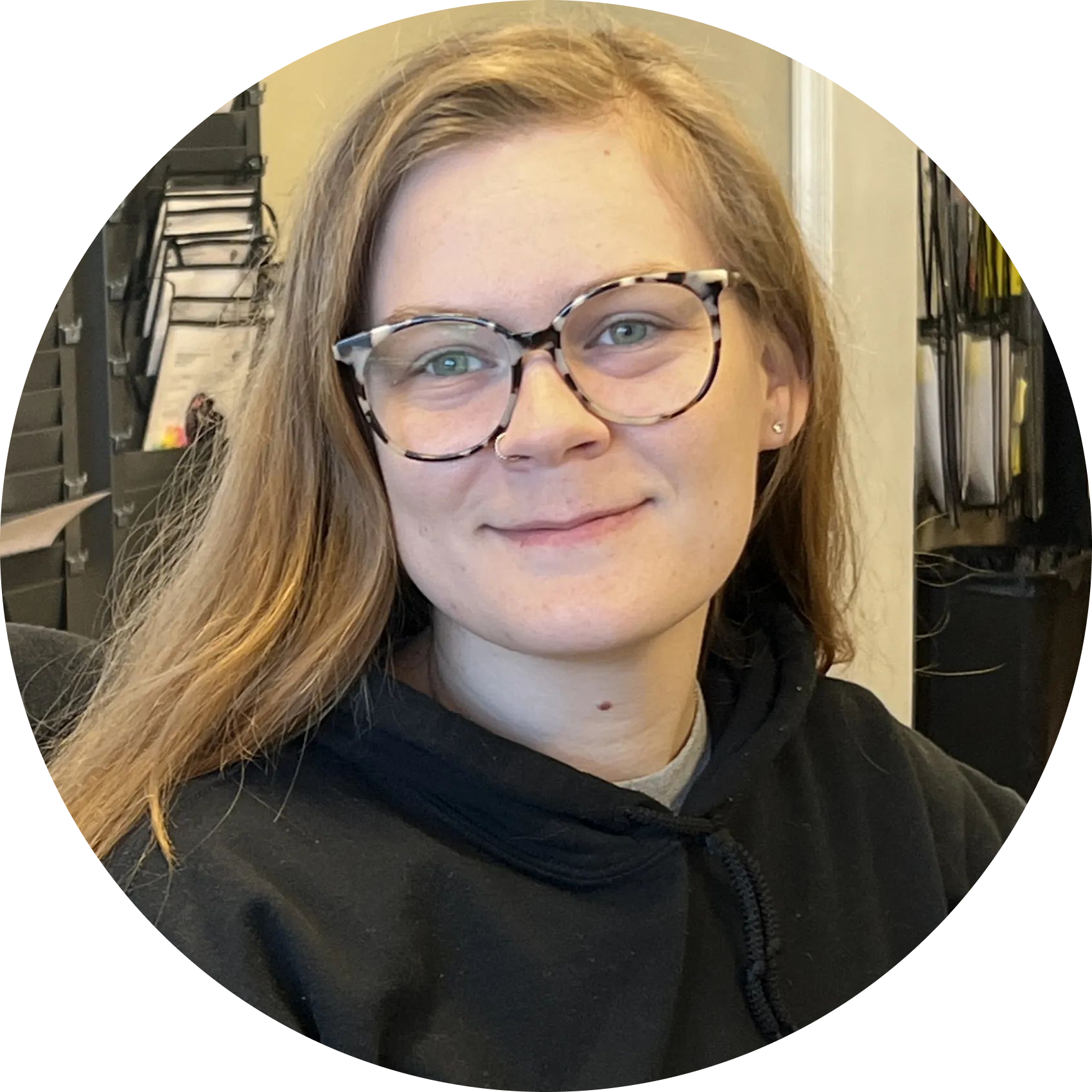 Person with glasses and a black hoodie smiling in a clothing store. | Denton Auto Care And Tire