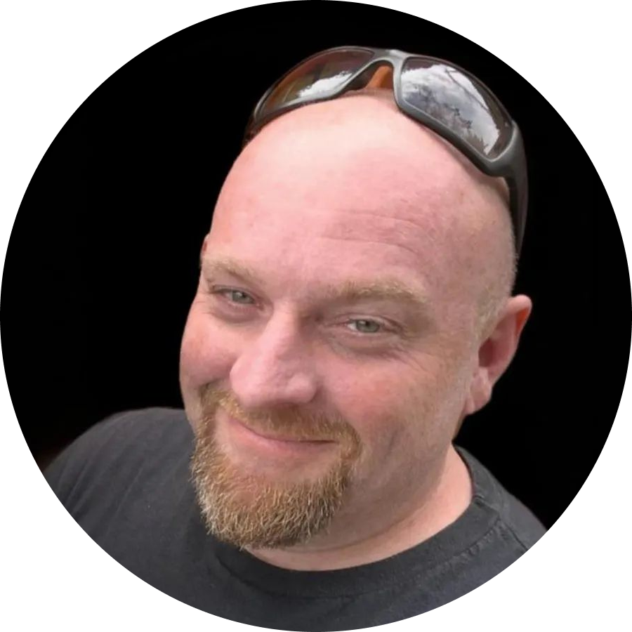 Smiling bald man with sunglasses on his head against a black background | Denton Auto Care And Tire
