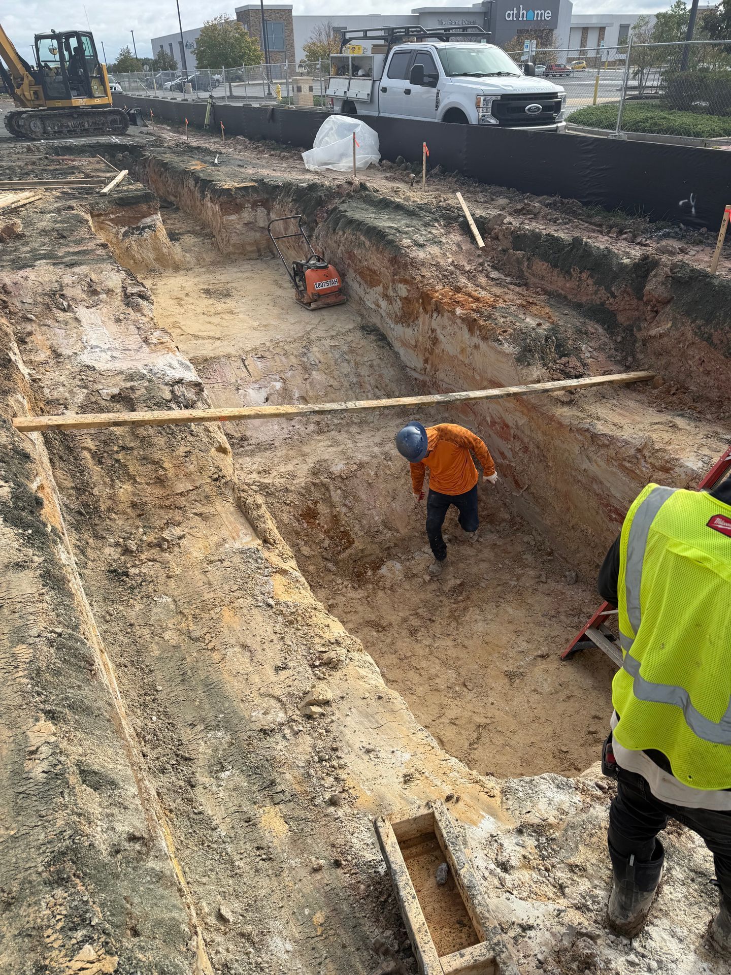 Workers in orange and yellow vests digging a trench at a road construction site