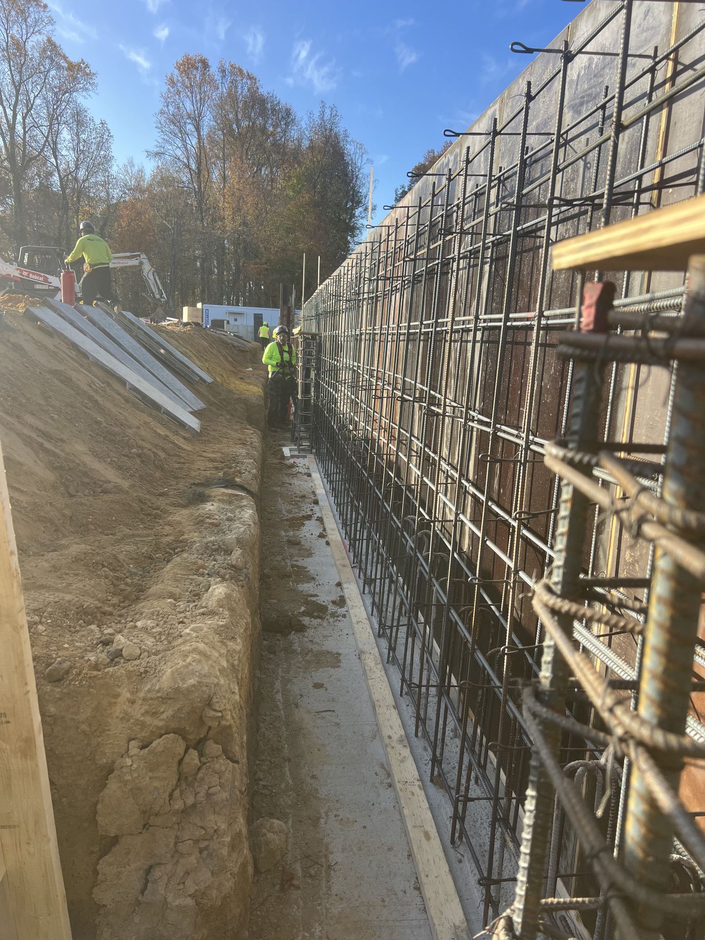 Workers beside a rebar wall in a trench at a construction site