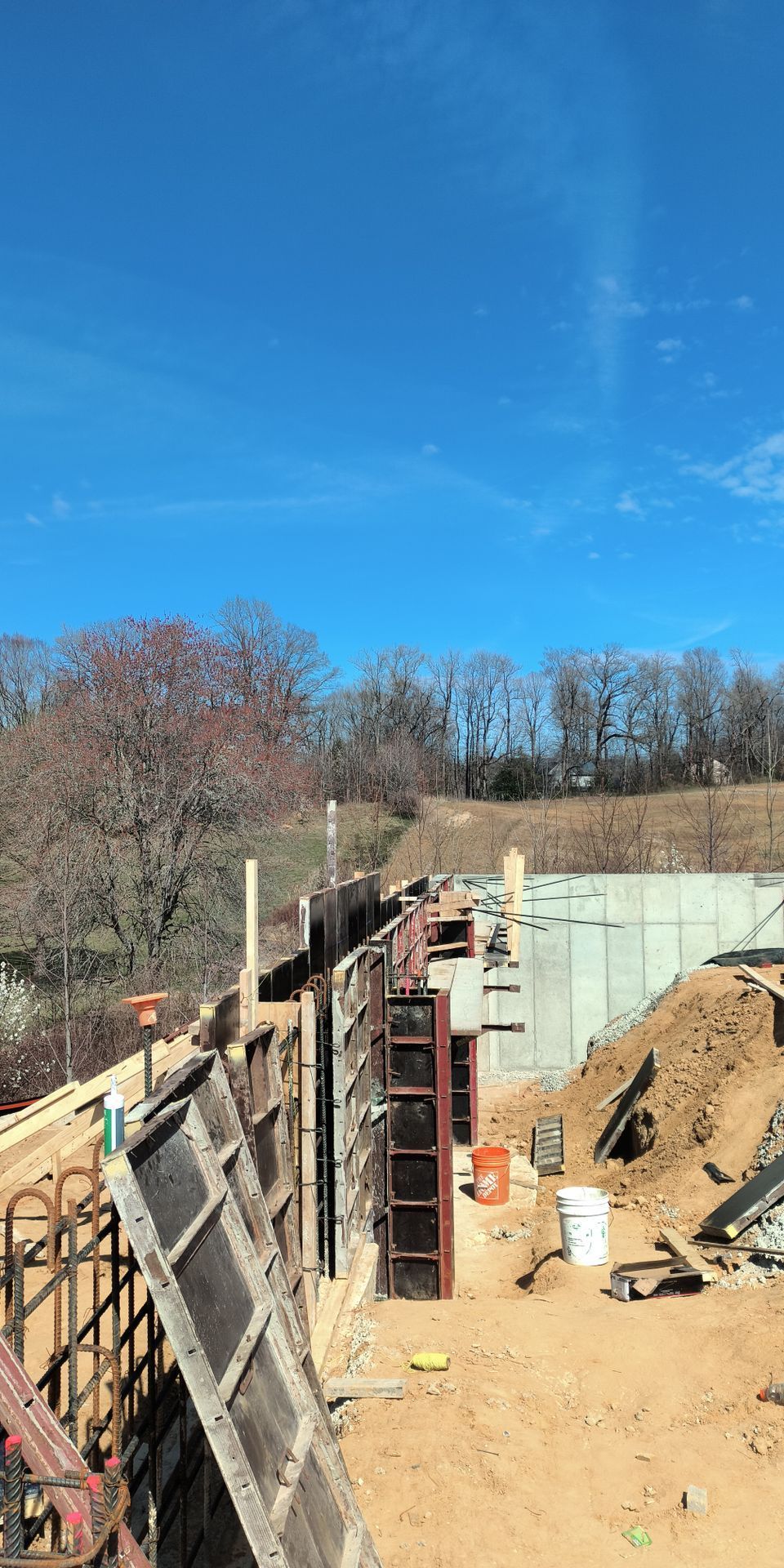 Construction site with foundation wall forms, dirt piles, and blue sky overhead
