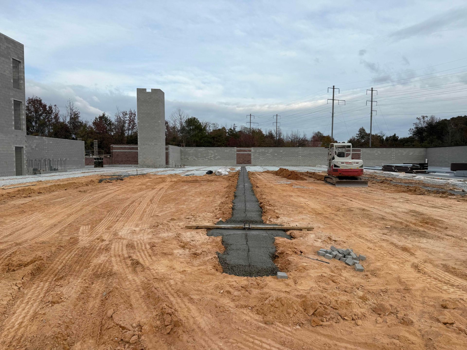 Construction site with concrete foundation, dirt ground, unfinished walls, and a parked white truck