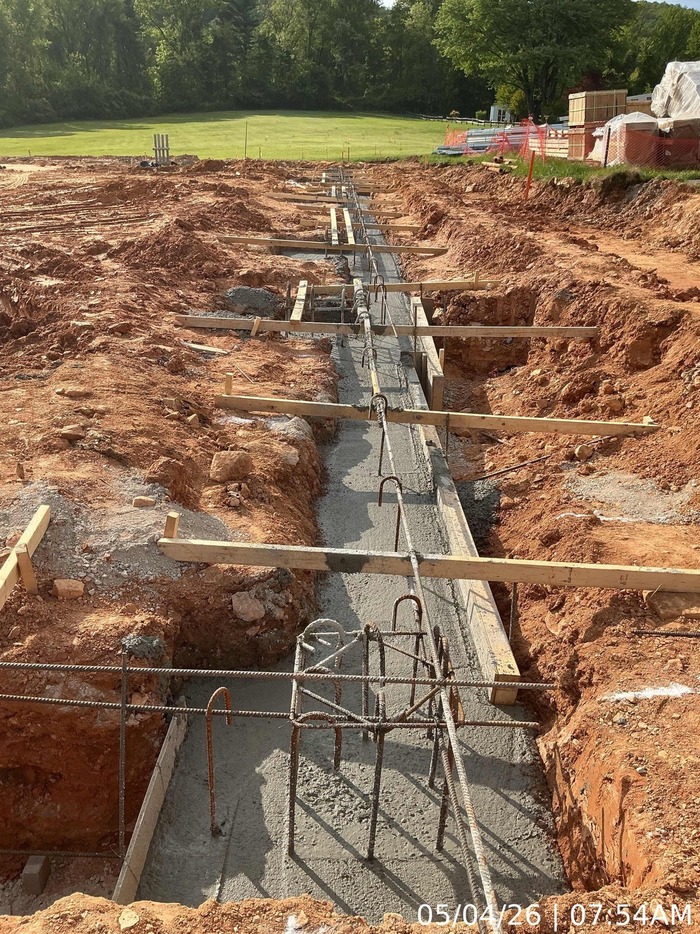 Trench with concrete footing and rebar for a building foundation at a construction site