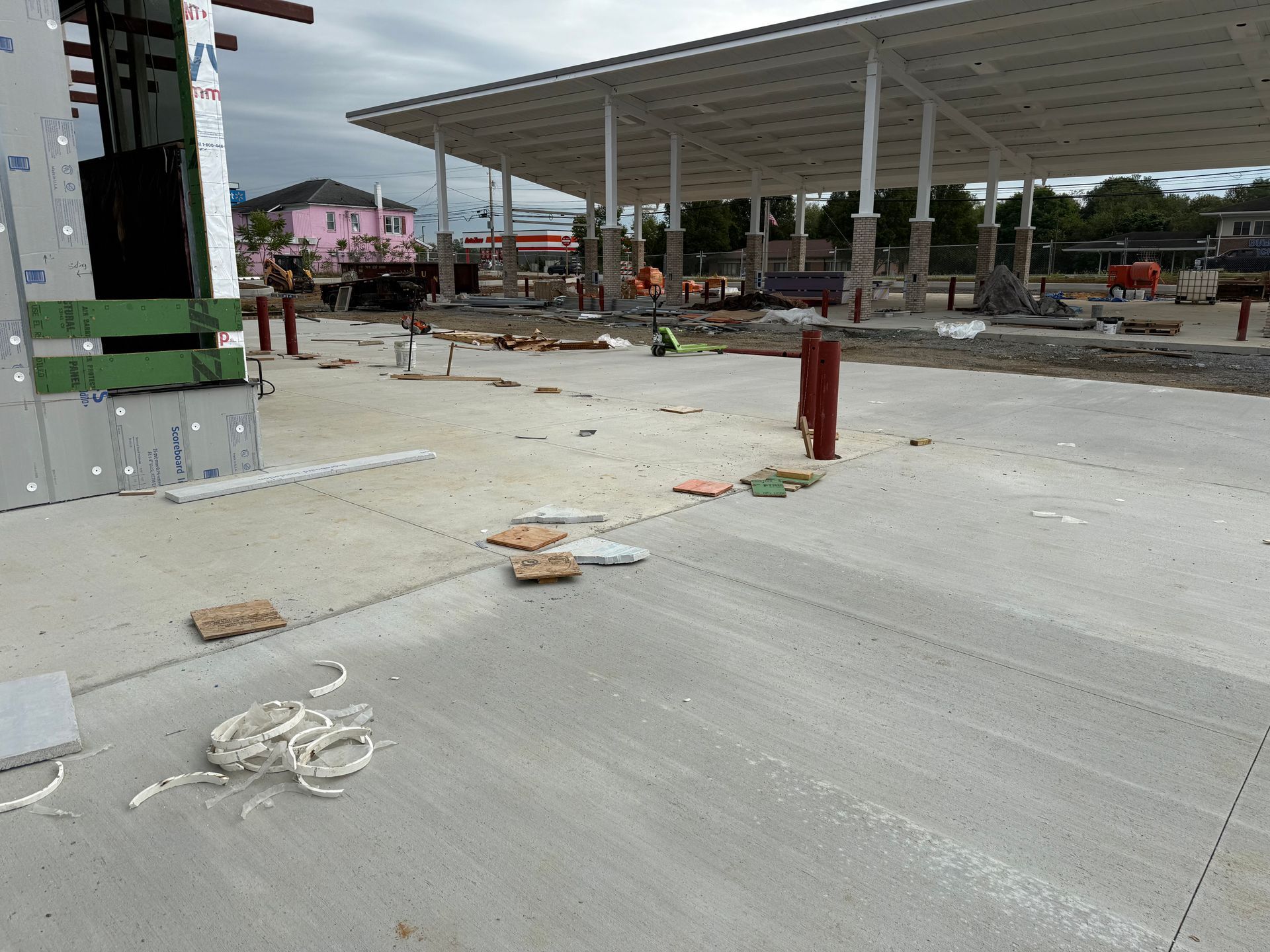 Empty concrete lot at a gas station under construction, with a canopy and scattered materials.