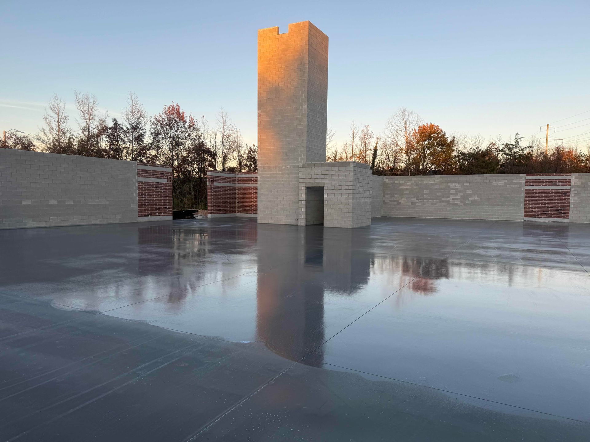 Reflective rooftop terrace at sunset with a central stone tower and surrounding walls