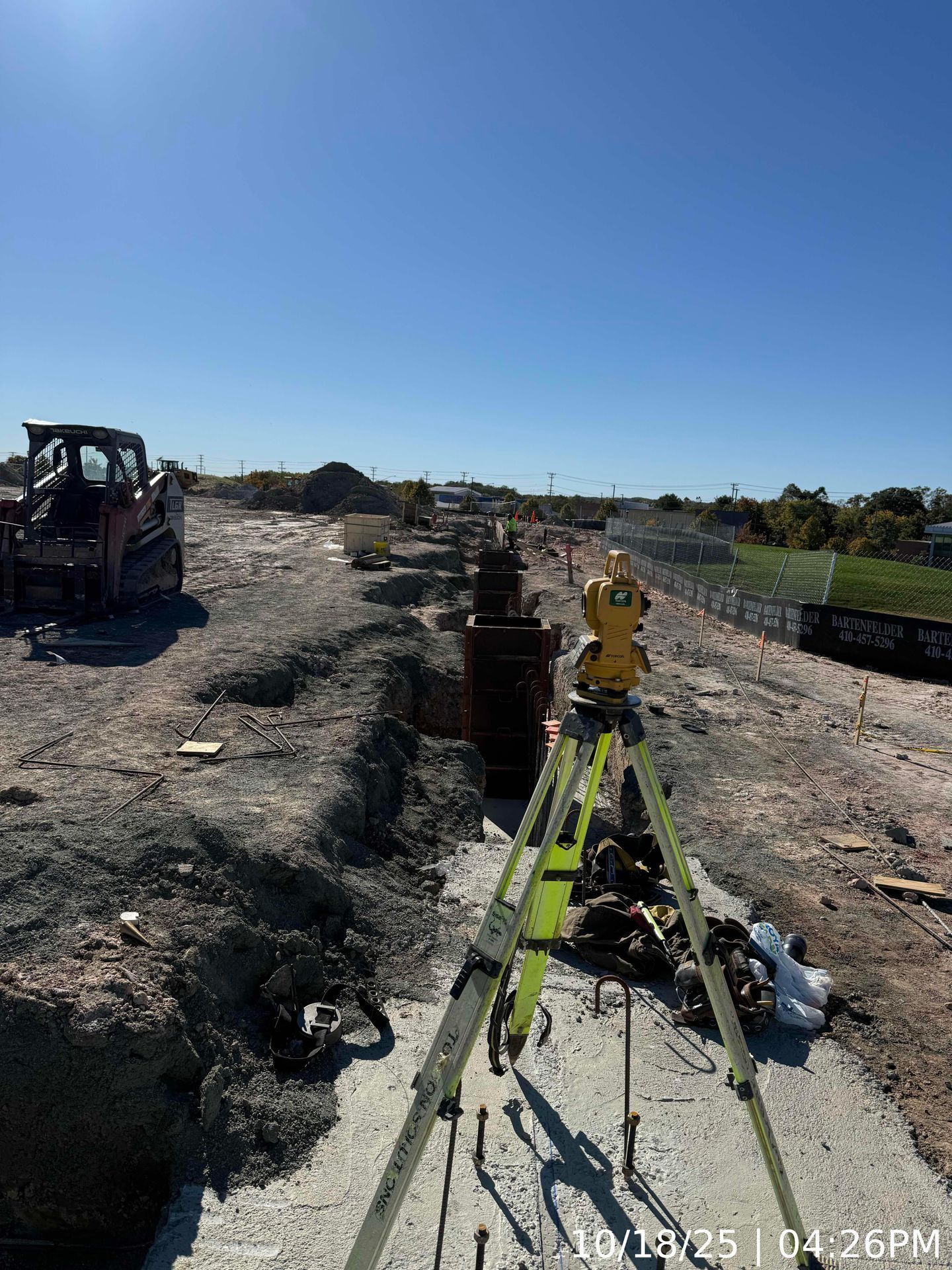 Surveying equipment on a dirt construction site under a clear blue sky
