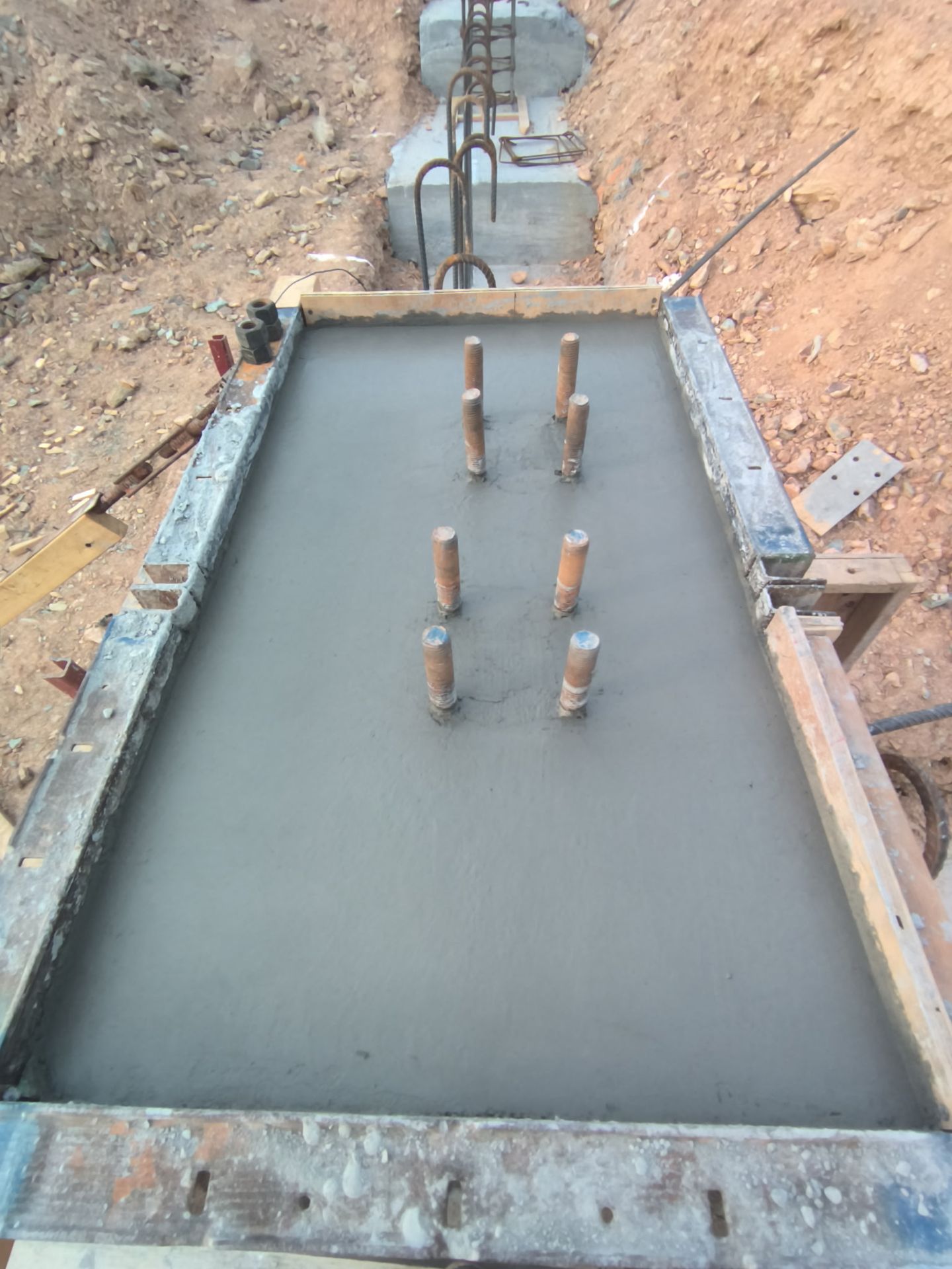 Fresh concrete foundation with rebar stubs in an excavation trench