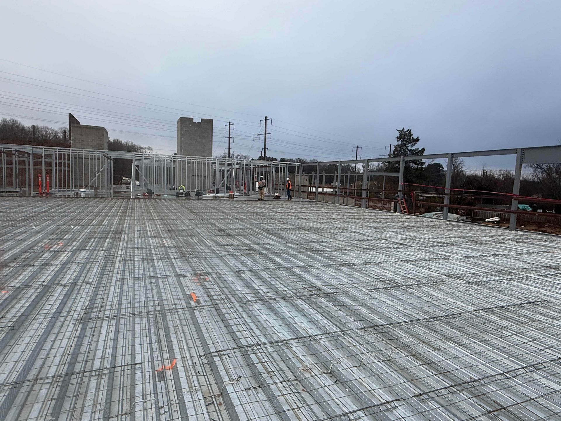 Construction site rooftop with exposed rebar and concrete forms under an overcast sky