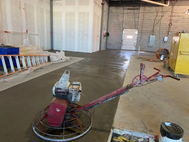 Power trowel smoothing fresh concrete inside an unfinished warehouse opening