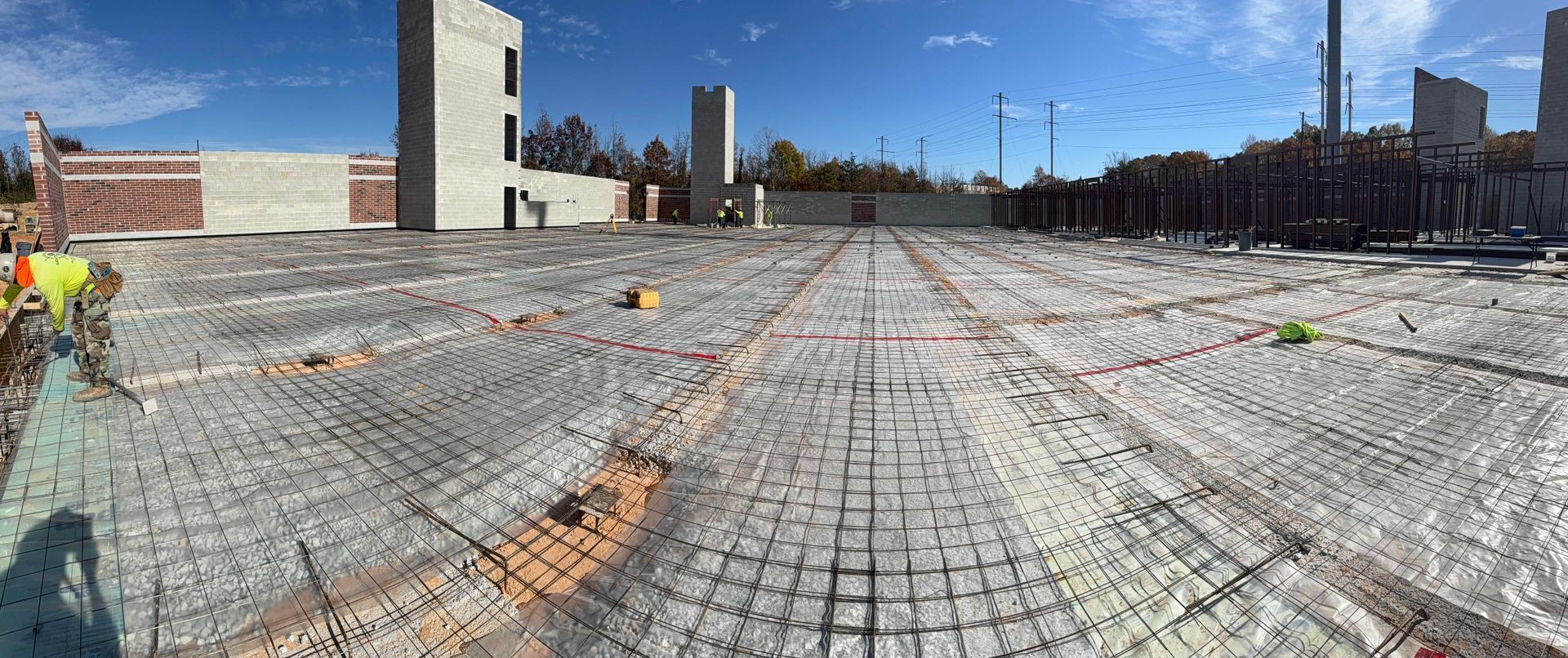 Empty construction site with steel rebar mesh and concrete columns under a blue sky