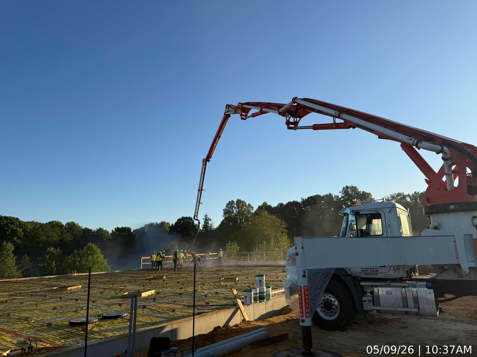 Construction crane pouring concrete at a worksite under a clear blue sky