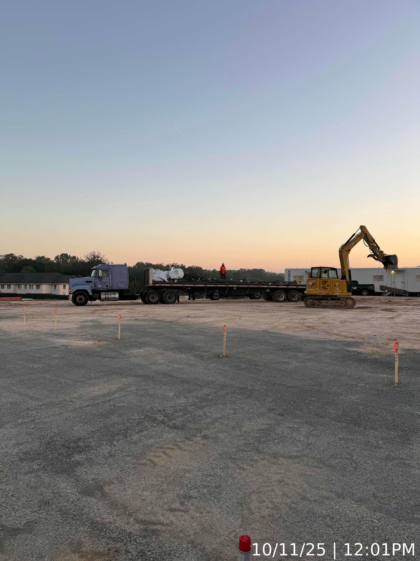 Truck and excavator at a gravel lot at sunset