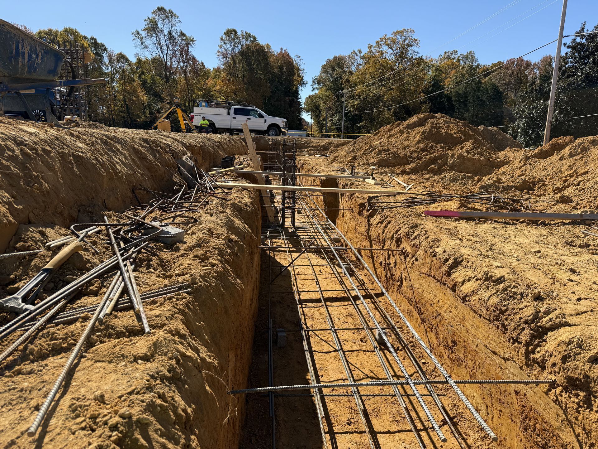 Excavation trench with rebar framework at a construction site under a clear sky