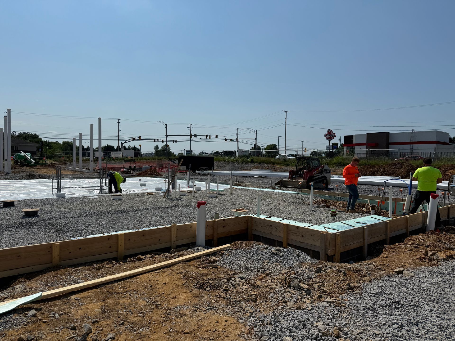 Construction workers pour concrete for a foundation at a building site under a clear sky
