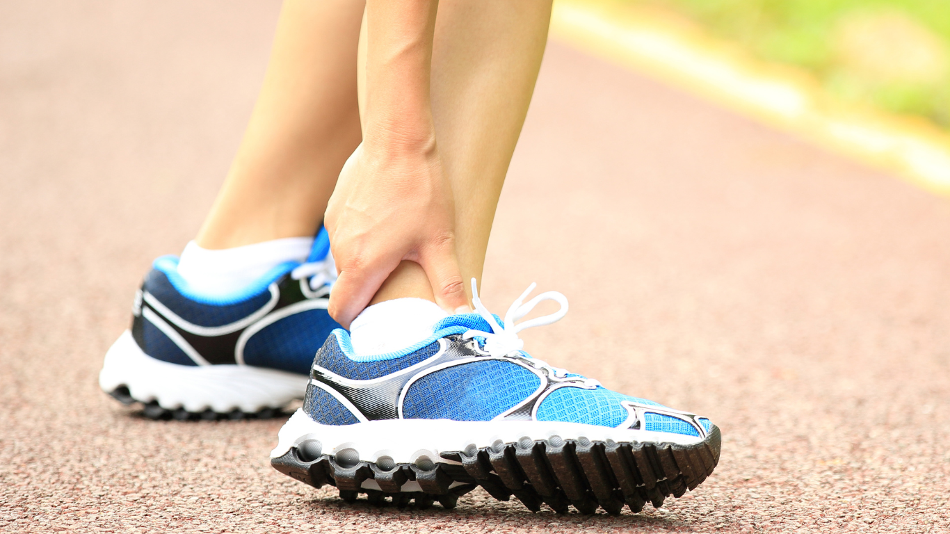 a person is holding their ankle in pain while running on a track .