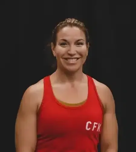 Woman in a red tank top smiles, arms flexed, with 