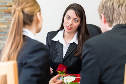 Eine Frau im Anzug hält eine Rose vor einer Gruppe von Menschen Eine Frau im Anzug hält eine Rose vor einer Gruppe von Menschen