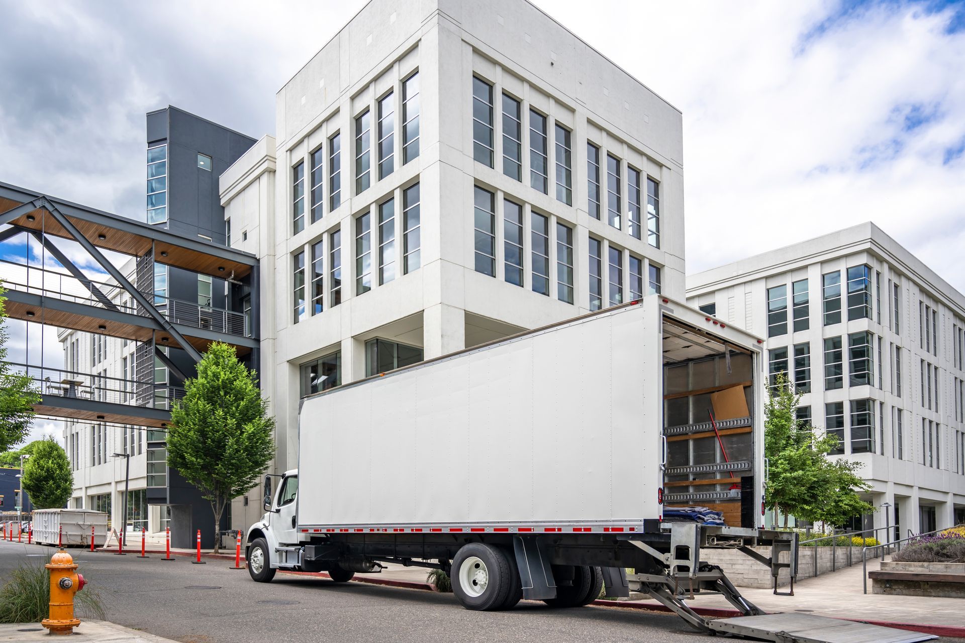 A white moving truck is parked in front of a large building.