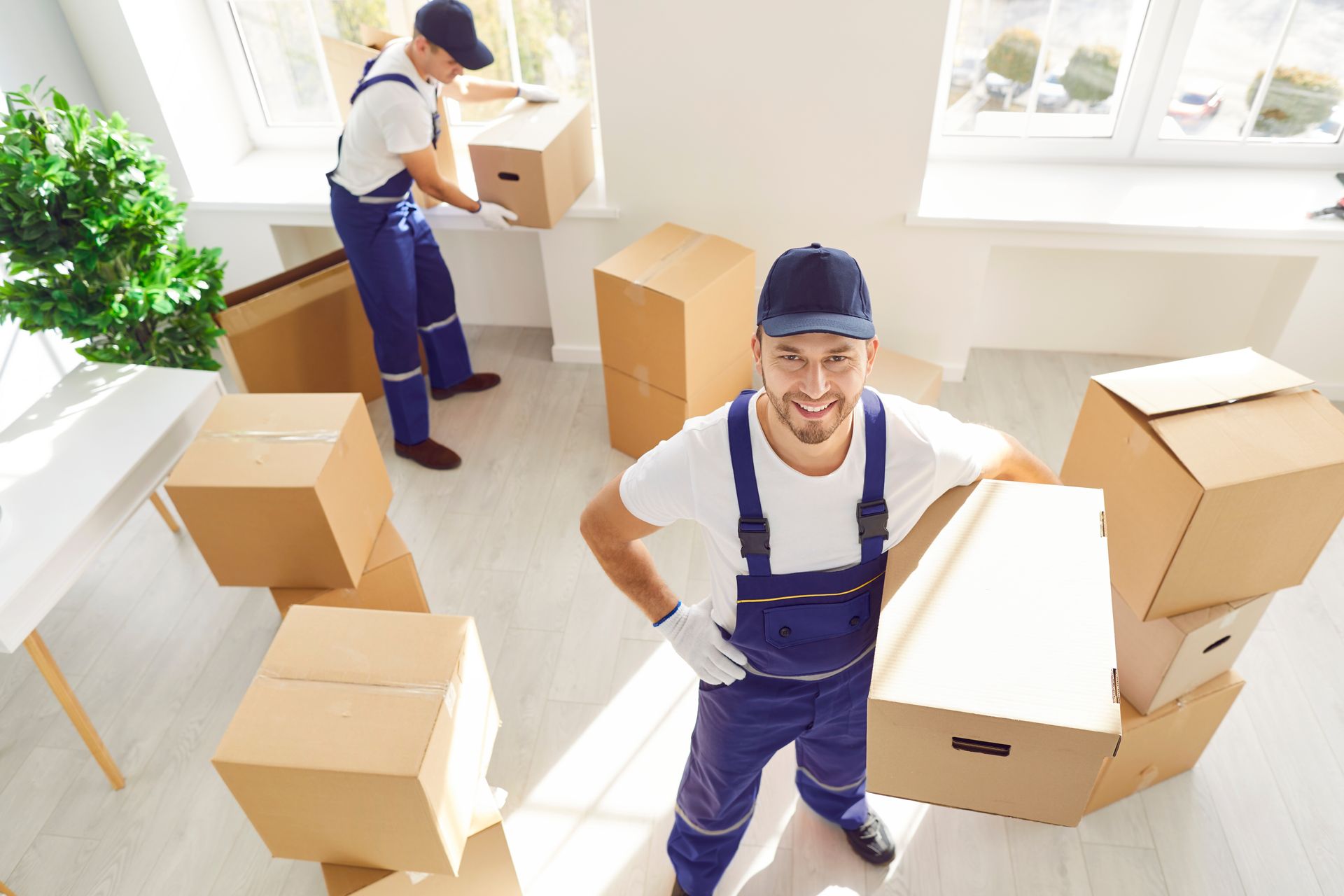 Two men are moving boxes in a room.