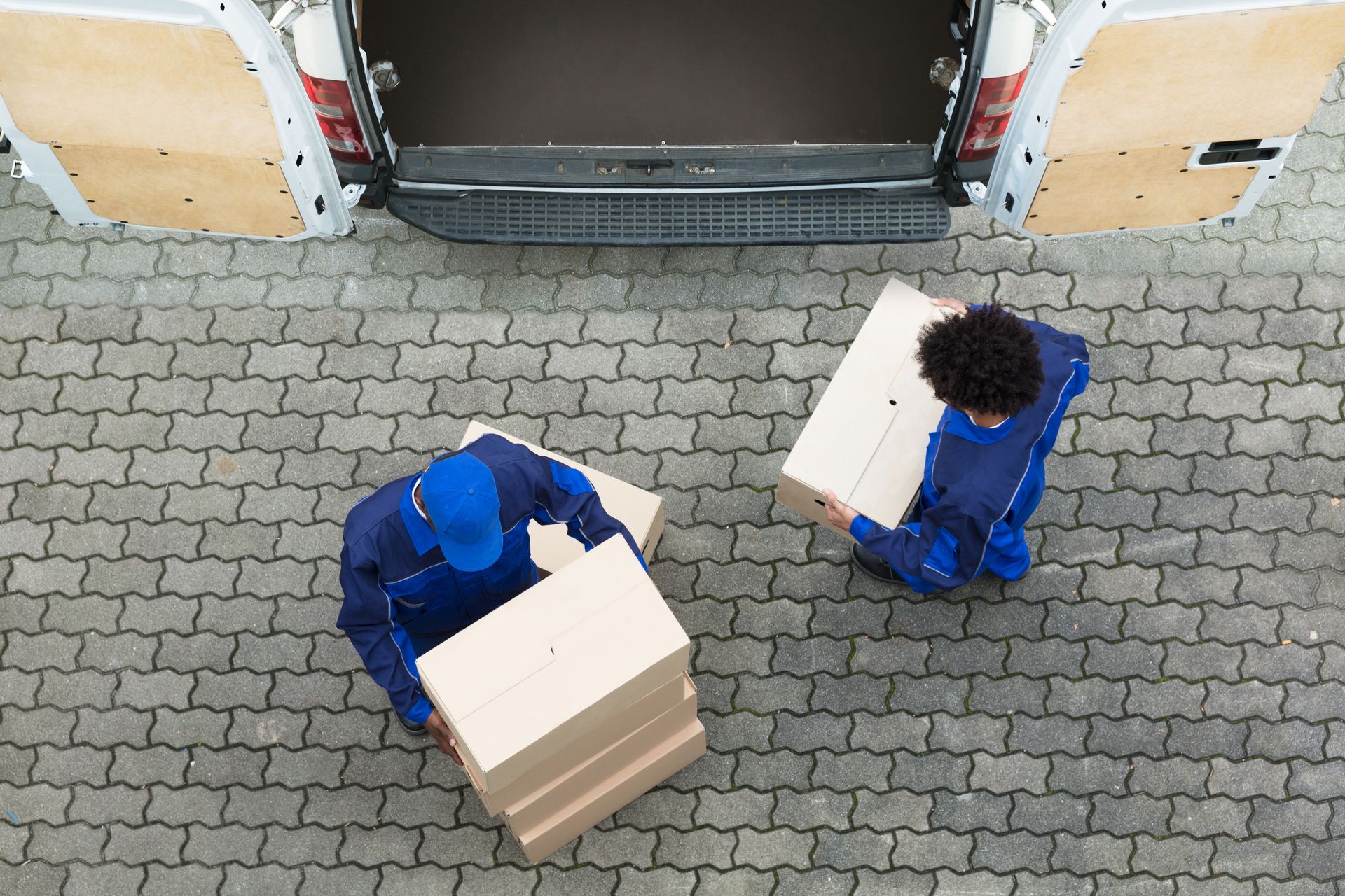 Two delivery men are carrying boxes out of a van.