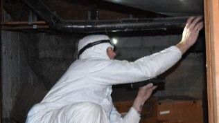 A man in a white suit is looking through a window
