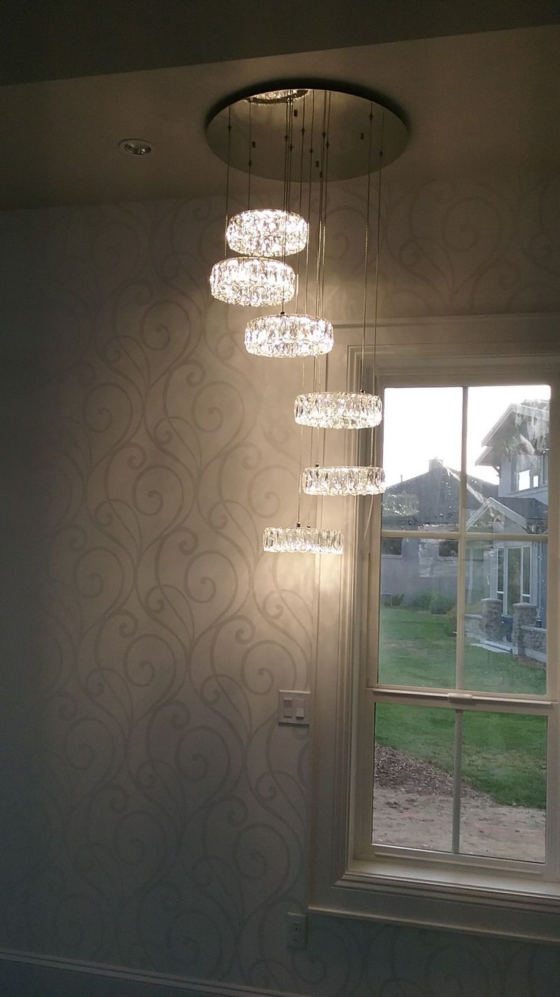 A chandelier is hanging from the ceiling in a room next to a window.
