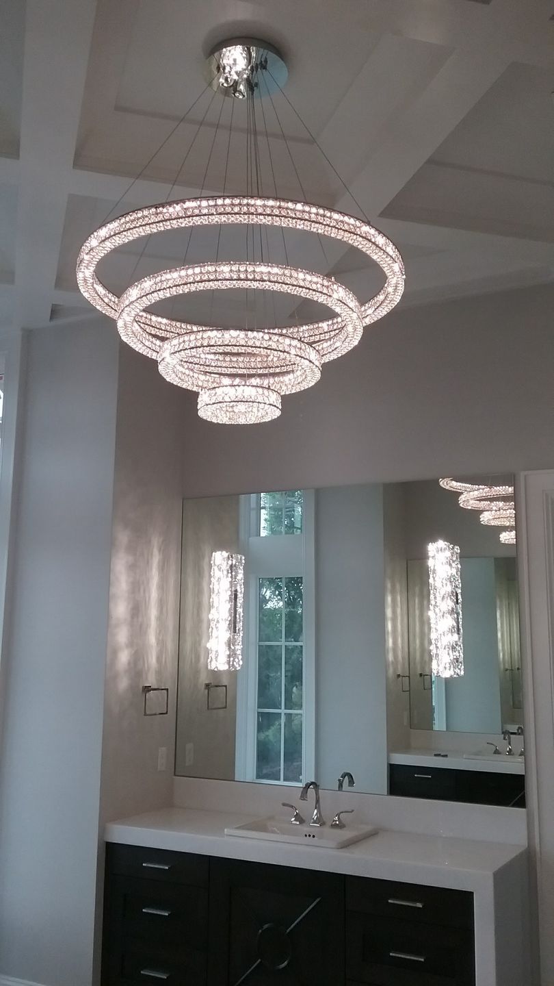 A bathroom with a sink and a chandelier hanging from the ceiling.