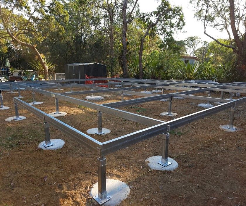 Metal frame foundation, on concrete pads, being built outdoors.