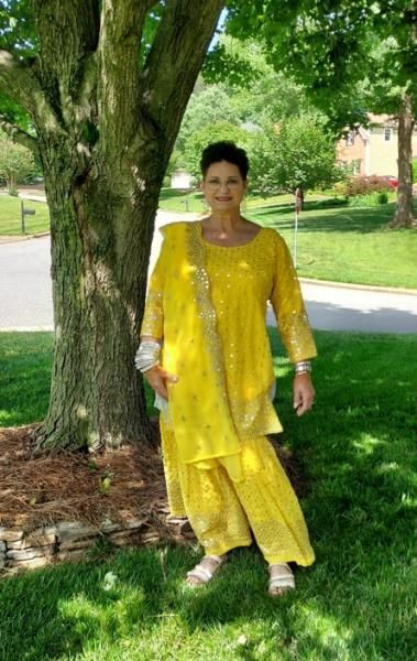 Person in a bright yellow outfit standing on grass beside a tree in a park