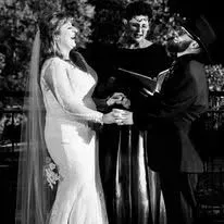 Bride and groom holding hands during an outdoor wedding ceremony with an officiant nearby