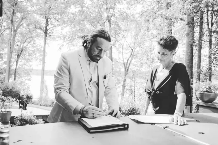 Two people signing documents at an outdoor table in a garden setting