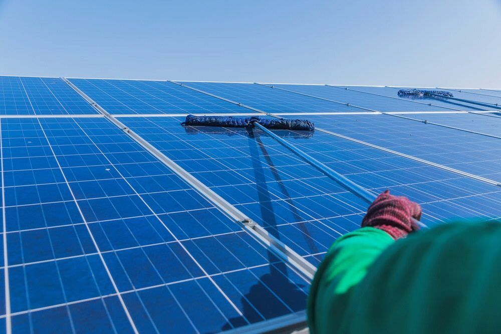 A Person Is Cleaning A Solar Panel With A Brush — Central West Budget Tree Services in Dubbo, NSW
