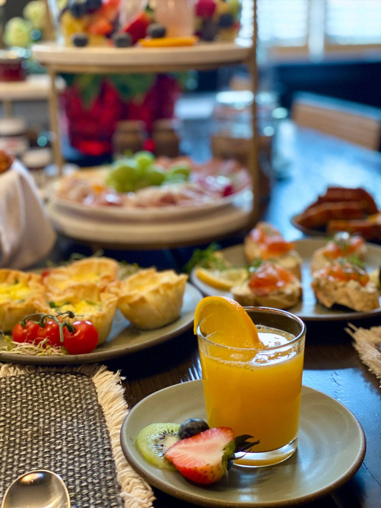 Brunch spread with pastries, fruit, and orange juice on a table by a window