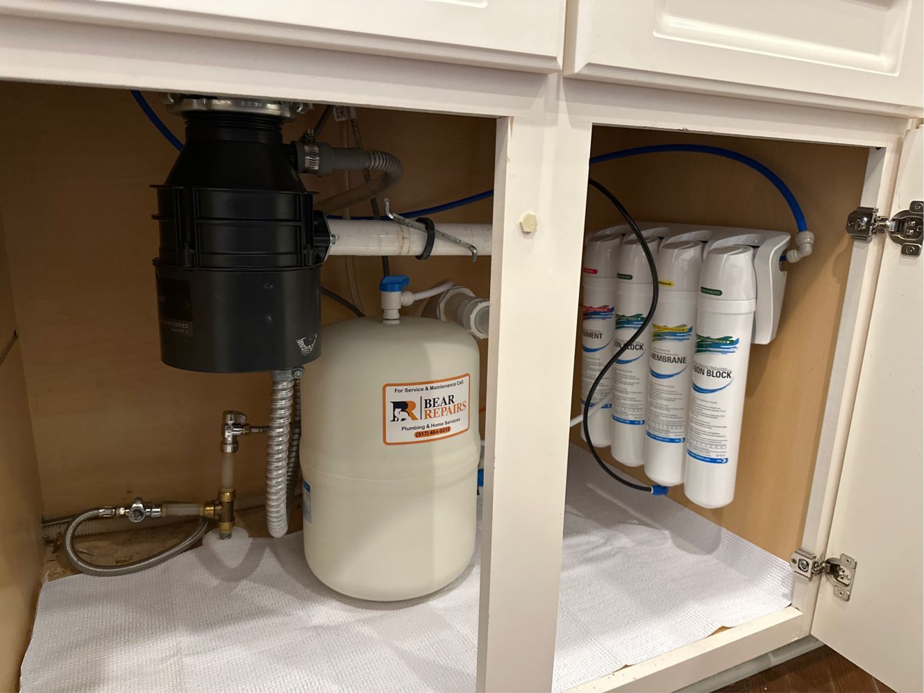 Under-sink cabinet with garbage disposal, water filter system, and pressure tank.