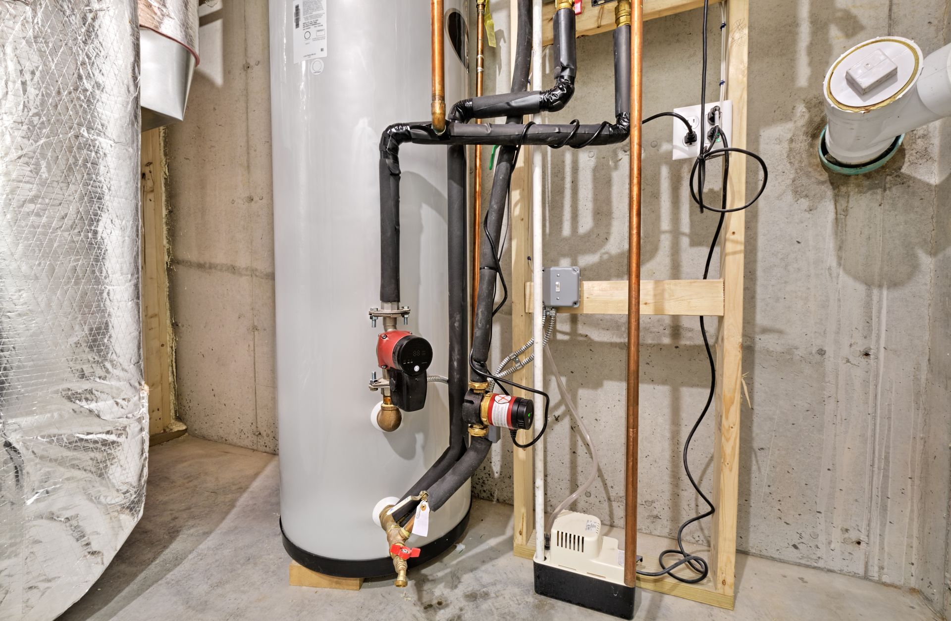 Basement utility room with water heater, pipes, wiring, and exposed concrete walls.
