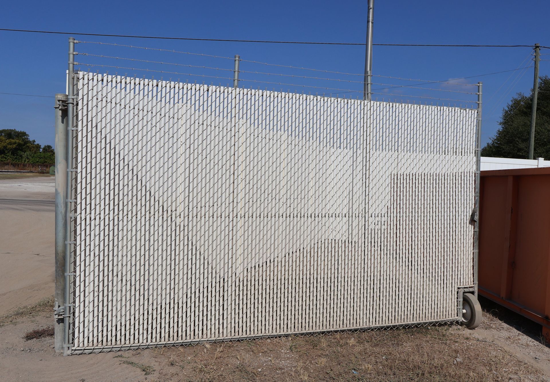 Commercial chain link and vinyl enclosure with barbed security wire on top in Tampa, FL