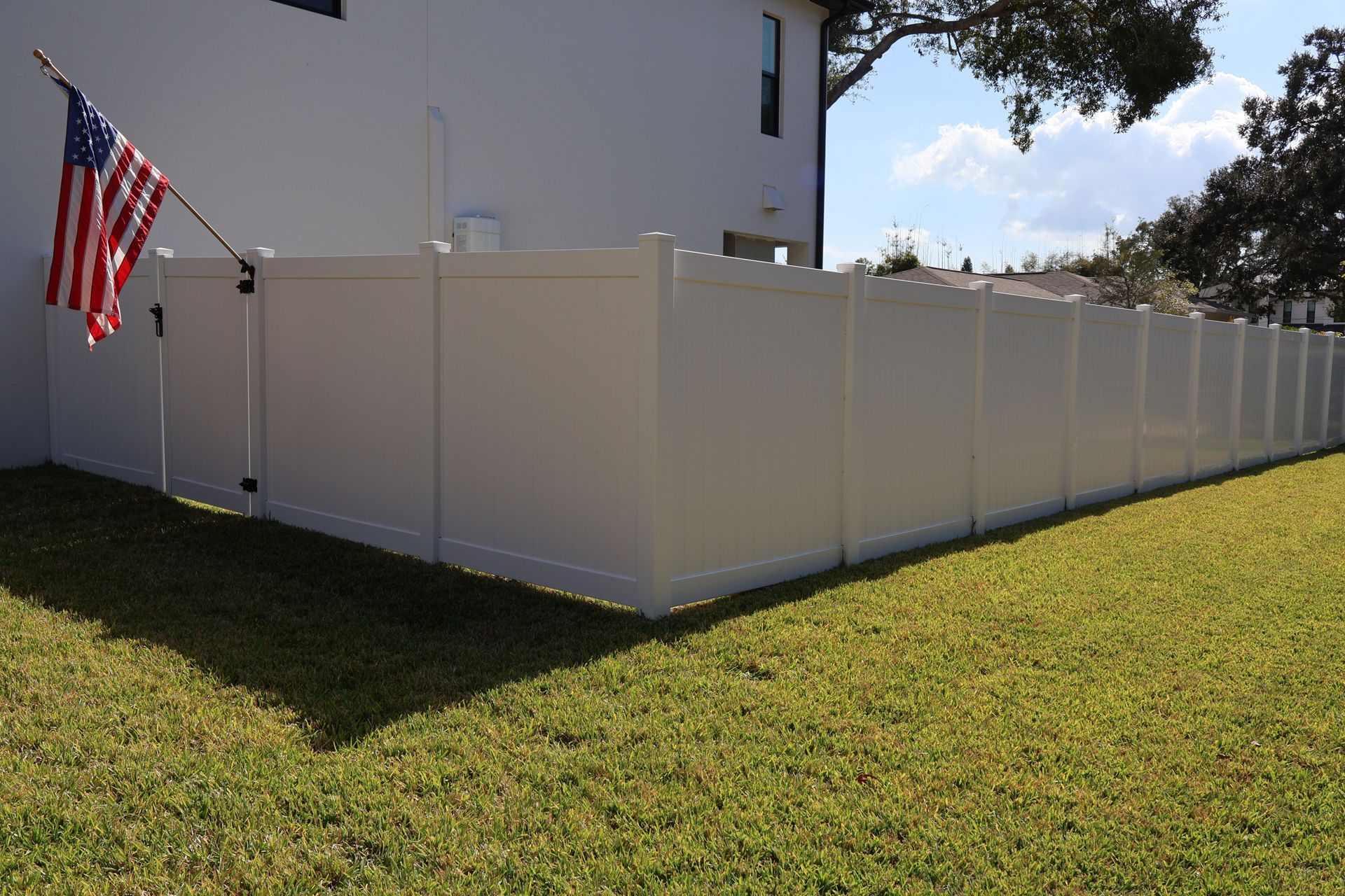 Residential PVC/Vinyl privacy fence installation in Tampa, FL with an American flag attached to the gate.