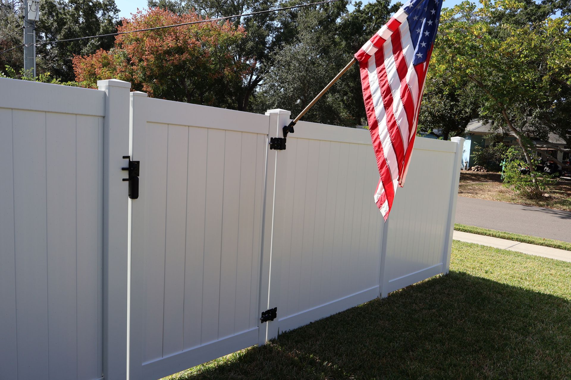 Residential PVC/Vinyl privacy fence with gate installation in Tampa, FL with an American flag attached to the gate