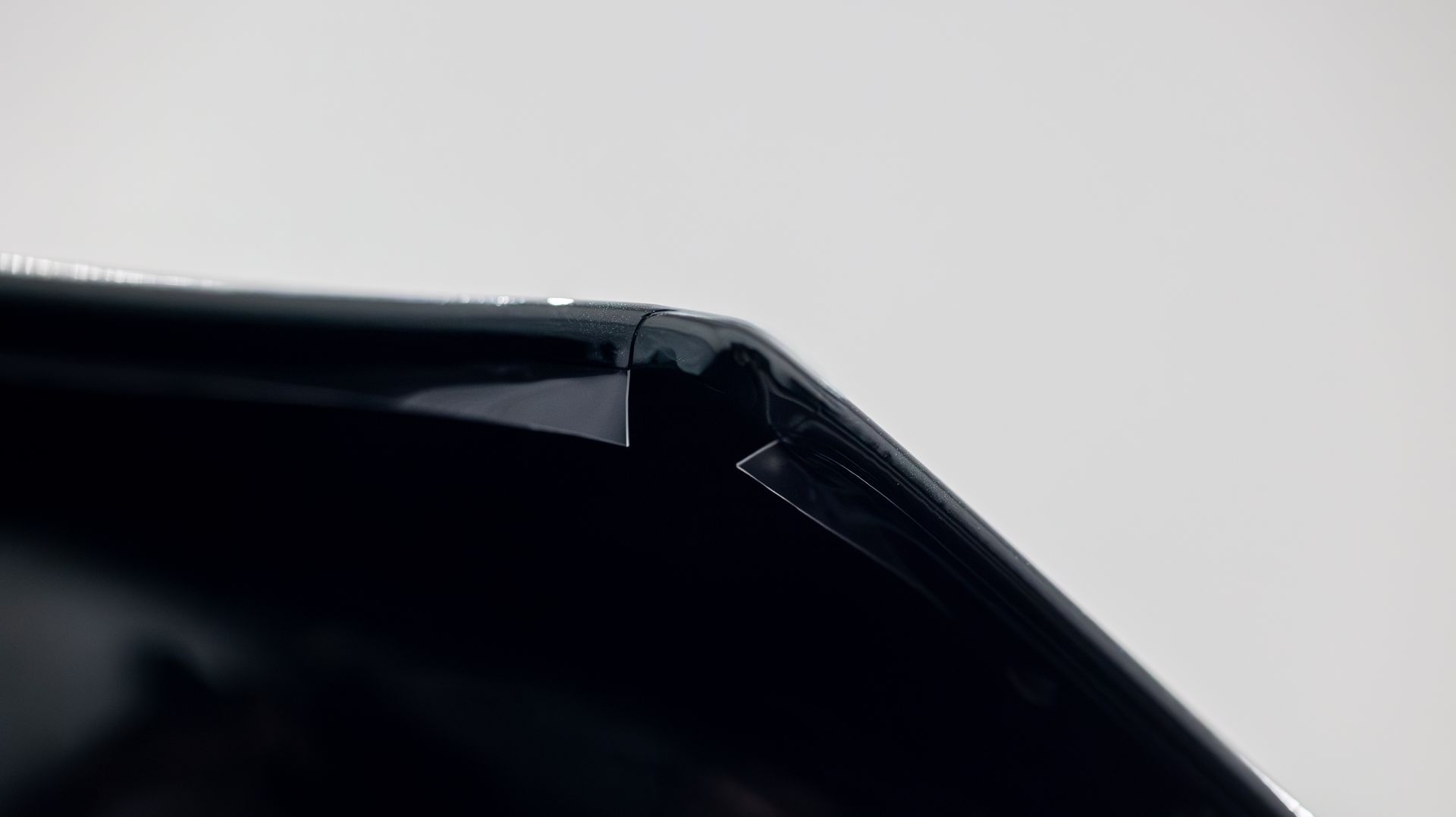 Close-up of a black angular object with a glossy edge against a light background