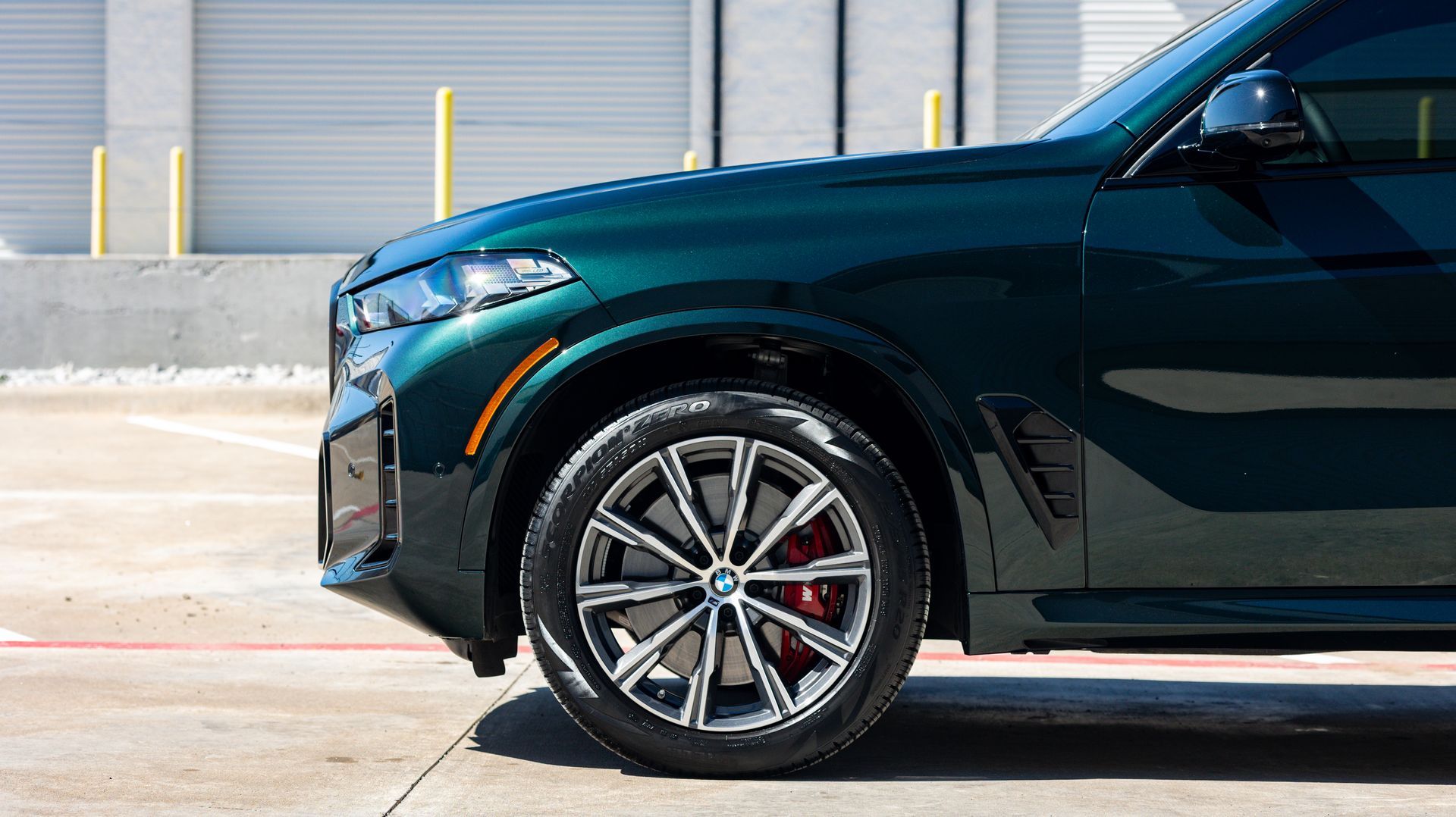Dark green SUV front side parked on concrete in front of a metal garage door
